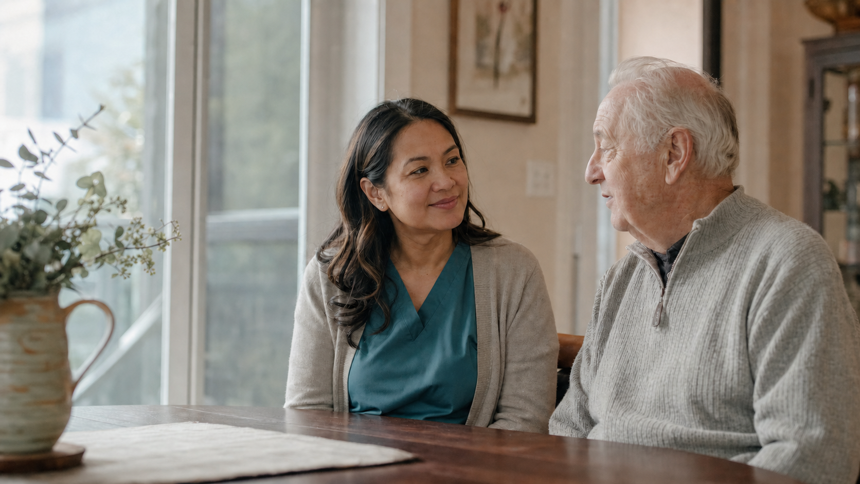 A nurse listens to an older man during a conversation in his home